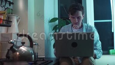 年轻人用电脑坐在厨房里<strong>烧水壶</strong>